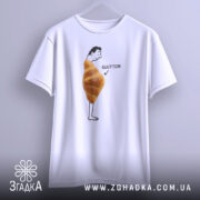 Футболка круасан гумор Glutton, біла, підвішена на вішалці, фон світло-сірий, принт з чоловіком, що стоїть з круасаном на животі та написом 'GLUTTON'.