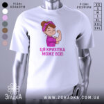 Футболка крихітка може все, біла футболка на манекені, з принтом дівчинки з червоною пов'язкою на голові, яка показує м'язи, текст під малюнком написаний фіолетовим кольором.