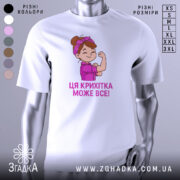 Футболка крихітка може все, біла футболка на манекені, з принтом дівчинки з червоною пов'язкою на голові, яка показує м'язи, текст під малюнком написаний фіолетовим кольором.