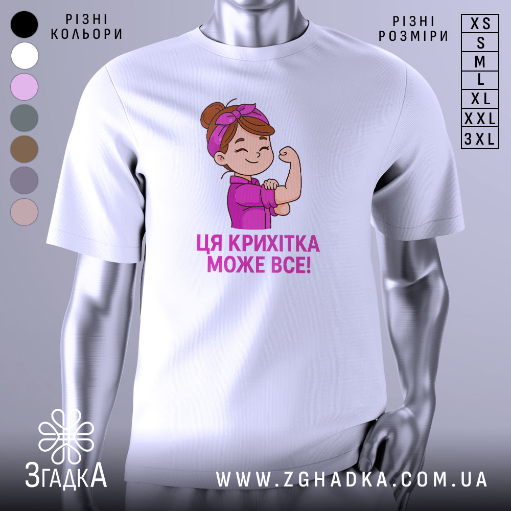 Futbolka Krykhitka Mozhe Vse Styl Dlia Vpevnenykh Divchat 1 Футболка крихітка може все, біла футболка на манекені, з принтом дівчинки з червоною пов'язкою на голові, яка показує м'язи, текст під малюнком написаний фіолетовим кольором.