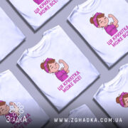 Футболка крихітка може все, біла футболка на манекені, з принтом дівчинки з червоною пов'язкою на голові, яка показує м'язи, текст під малюнком написаний фіолетовим кольором.