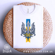 Футболка крила меч свободи, біла, складена на кошику, фон світло-сірий, принт з мечем та крилами, видима етикетка на горловині.