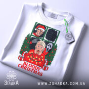 Футболка криваве різдво, біла, зображена зверху, на ній підвішений етикетка, фон світлий, принт аналогічний попередньому, з акцентом на деталі та текст.