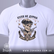 Футболка куля не дурна, біла, складена на поверхні, фон світло-сірий, принт з черепом у капелюсі, двома пістолетами та написом 'Куля не дурна', на футболці є етикетка з зеленим шнурком.