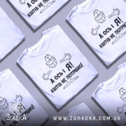 Футболка квітів не потрібно. Біла футболка з коротким рукавом, зображена на манекені з блискучою поверхнею. На футболці чорний принт з усміхненим персонажем і текстом "А ось і Я! Квітів не потрібно!". Фон світло-сірий, що підкреслює яскравість принта.