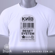 Футболка Київ білого кольору, складена на поверхні, фон світлий, принт у вигляді штрих-коду з написами 'Київ', 'RESET SYSTEM', 'CITY OF CHESTNUTS' та 'SCAN FOR FREEDOM', на комірці видна етикетка.