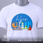 Футболка Київ міський стиль, біла, з верхнього ракурсу, складена на поверхні, фон світло-сірий, принт з зображенням архітектурних пам'яток Києва, з етикеткою на рукаві.
