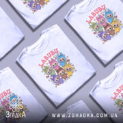 Футболка labubu білого кольору, зображена з фронтального ракурсу на манекені, фон світло-сірий, принт містить кольорові персонажі з великими очима та зірочками навколо.