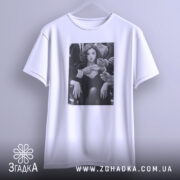 Футболка леді у центрі уваги, біла, підвішена на вішалці, на фоні світлого градієнта, принт з чорно-білим зображенням жінки з сигаретою, руки оточують її.