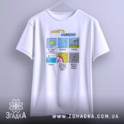 Футболка любіть Україну, білого кольору, підвішена на вішалці, фон світлий, принт з кольоровими малюнками, текст розташований у верхній частині футболки.