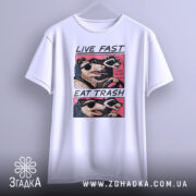 Футболка Live Fast Eat Trash білого кольору, підвішена на вішалці, ракурс спереду, фон світло-сірий, принт з двома тваринами в окулярах, текст на футболці чорний і рожевий.