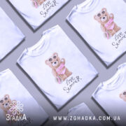 Футболка Love Summer Bear, біла, зображена на манекені, фон нейтральний, принт з ведмедиком у купальнику з рожевими рюшами та сонцезахисними окулярами, напис 'Love Summer' під принтом.