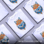 Футболка лисиця білого кольору, зображена на манекені, з принтом лисиці в яскравих кольорах, фон світло-сірий, деталі принта включають оранжеві та блакитні відтінки, а також геометричні елементи.
