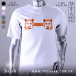 Футболка лисицьки білого кольору, зображена з фронтального ракурсу на манекені, фон світлий, принт з двома лисицями та написом 'ЛИСИЦЬКИ' оранжевого кольору.