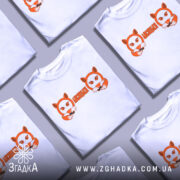 Футболка лисицьки білого кольору, зображена з фронтального ракурсу на манекені, фон світлий, принт з двома лисицями та написом 'ЛИСИЦЬКИ' оранжевого кольору.