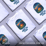 Футболка магія нічного лісу, біла, зображена з фронтального ракурсу, на фоні світло-сірого градієнта, принт з малюнком намету, гір та зірок на нічному небі.