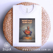 Футболка малий робот надії білого кольору, зображена зверху на плетеній кошику, фон світлий, принт з малюнком робота в червоному костюмі з написом 'МАЛИЙ РОБОТ. ВЕЛИКІ НАДІЇ.'