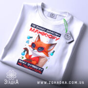 Футболка манікюр з характером, біла, складена на поверхні, фон світло-сірий, принт з лисом у сонцезахисних окулярах, текст червоний і чорний, на футболці є етикетка з логотипом.