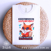 Футболка манікюр з характером, біла, складена на плетеній кошику, фон світло-сірий, принт з лисом у сонцезахисних окулярах, текст червоний і чорний, видима етикетка з логотипом.