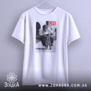 Футболка мавпа на велосипеді, біла, підвішена на вішалці, фон світлий, принт зображає мавпу на велосипеді з написом 'LIFE'.