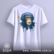 Футболка мавпа в навушниках, біла, зображена на вішалці з фронтального ракурсу, фон світло-сірий, принт зображає мавпу в навушниках з кольоровими плямами та метеликами.