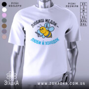 Футболка медок холодок, біла, зображена на манекені, фон світло-сірий, принт з бджолою, яка тримає пістолети, текст чорного та блакитного кольору.