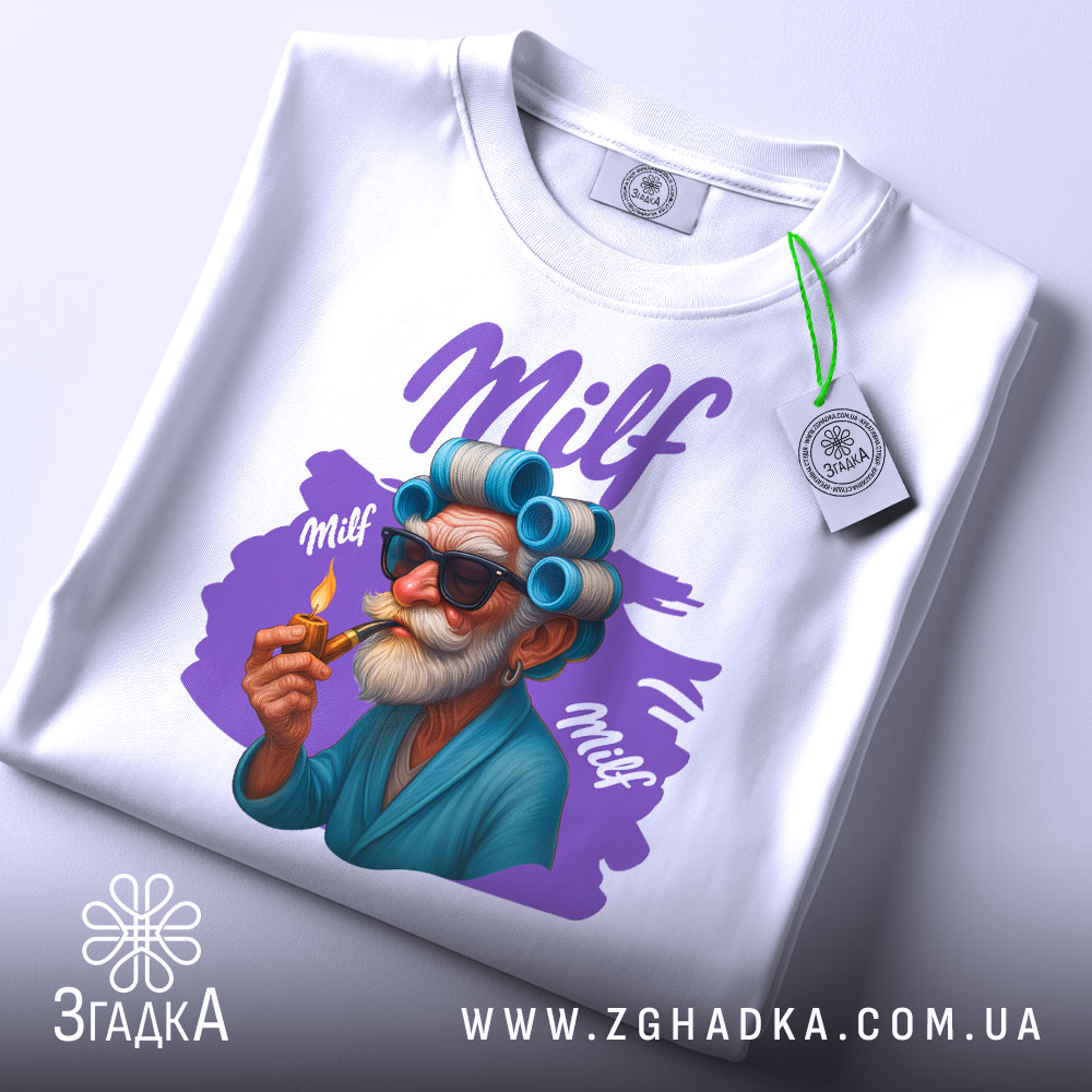 Футболка milf білого кольору, складена на столі, з принтом старшого чоловіка в окулярах та з бігуді, який тримає сигарету, фон світло-сірий, на футболці є етикетка з логотипом.