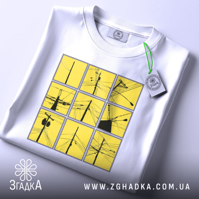 Футболка міські дроти, біла, зображена на столі, фон світло-сірий, принт складається з дев'яти квадратів жовтого кольору з чорними малюнками дротів, на футболці є етикетка.