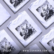 Футболка моя пісня зброя, біла футболка на манекені, ракурс спереду, фон світло-сірий, принт з зображенням кобзаря, який грає на бандурі, з написом 'Моя пісня - моя зброя'.