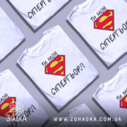 Футболка моя супергьорл, біла, зображена з фронтального ракурсу, фон світло-сірий, принт з червоним логотипом Супермена та текстом "ТИ МОЯ СУПЕРГЬОРЛ" чорного кольору.