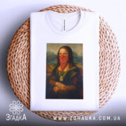Футболка Мона Ліза білого кольору, лежить на плетеній основі, фон світло-сірий, принт зображає Мону Лізу в червоній бандані, з видимими деталями принта.