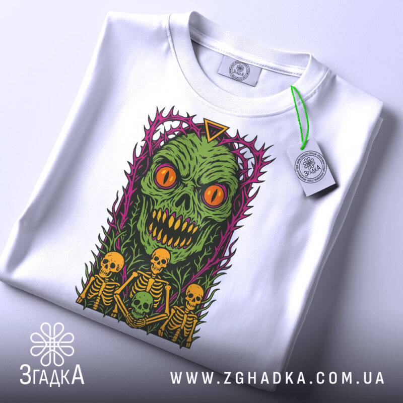 Футболка монстр і скелети, біла, зображена зверху, фон світло-сірий, принт з зеленим монстром з оранжевими очима, прикрашений фіолетовими колючками, на футболці є етикетка.