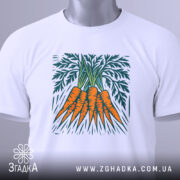 Футболка морква арт, біла, складена на поверхні, фон світло-сірий, принт зображує три помаранчеві морквини з зеленим листям, на комірці є етикетка.