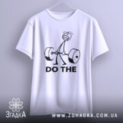 Футболка мотивація для залу, біла, зображена на вішалці, фон світло-сірий, принт з малюнком людини, що піднімає штангу, та текстом 'DO THE' чорного кольору.