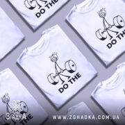 Футболка мотивація для залу, біла, зображена з правого ракурсу на манекені, фон світло-сірий, принт з малюнком людини, що піднімає штангу, та текстом 'DO THE' чорного кольору.