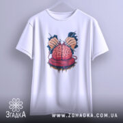 Футболка мозок в клубку, біла, зображена на вішалці, на світло-сірому фоні, принт з червоним мозком, що оточений руками з голками та клубком червоної пряжі.