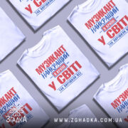 Футболка музикант білого кольору, зображена на манекені, з принтом червоного та синього кольорів, текст розташований по центру, фон світло-сірий.