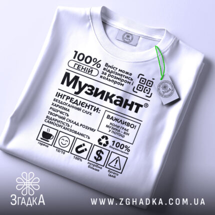 Футболка музикант білого кольору, складена на поверхні, з принтом у чорному кольорі, на фоні світло-сірого кольору, з зеленим ярликом, що звисає з коміра.