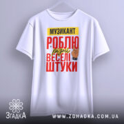 Футболка музикант білого кольору, підвішена на вішалці, фон світло-сірий, принт з текстом "МУЗИКАНТ РОБЛЮ різні веселі штуки" в червоному, жовтому та чорному кольорах, з малюнком руки в жесті рок-знака.