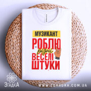 Футболка музикант білого кольору, складена на плетеній основі, фон світлий, принт містить текст "МУЗИКАНТ РОБЛЮ різні веселі штуки" в червоному, жовтому та чорному кольорах, з малюнком руки в жесті рок-знака.