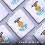 Футболка музикант, біла, зображена з правого ракурсу на манекені, фон світло-сірий, принт з медаллю та текстом "ГАРНИЙ МУЗИКАНТ знає все І навіть більше..." у яскравих кольорах.