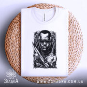 Футболка мисливець на морок, біла, лежить на плетеній кошику, фон світло-сірий, принт чорного кольору з зображенням чоловіка в окулярах, з мечем і черепом.