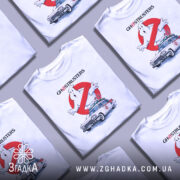Футболка мисливці за привидами, біла, показана з фронтального ракурсу на манекені, фон світло-сірий, принт з зображенням привида та автомобіля з фільму, з написом 'GHOSTRUSTERS'.