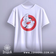 Футболка мисливці за привидами, біла, підвішена на вішалці, фон світло-сірий, принт з привидом, що тримає червоне сердечко в руках, з округлими рукавами.