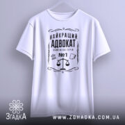 Футболка найкращий адвокат, біла, зображена з фронтального ракурсу на вішалці, фон світло-сірий, принт чорного кольору з зображенням ваг та текстом.