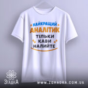 Футболка найкращий аналітик, білого кольору, підвішена на вішалці, фон світло-сірий, принт з текстом синього та оранжевого кольорів, з кавовими зернами.