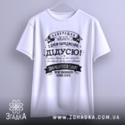 Футболка найкращий дідусь планети, біла, підвішена на вішалці, фон світлий, принт чорного кольору з текстом на українській мові, оформлений у стилі ретро з декоративними елементами.