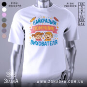 Футболка найкращий помічник вихователя, білого кольору, зображена на манекені, фон світло-сірий, принт містить малюнки двох дітей з усмішками, олівці та зірочки навколо тексту.