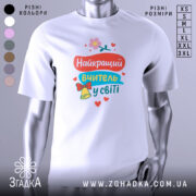 Футболка найкращий вчитель, біла, зображена на манекені, фон світло-сірий, принт містить яскраві кольори: червоний, блакитний, жовтий, з квіткою та дзвоником.