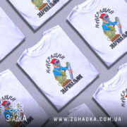 Футболка Найкращий зварювальник, білого кольору, зображена на манекені з правого ракурсу, фон світло-сірий, принт з малюнком зварювальника у синій куртці та червоній касці, що працює з електродом, текст на футболці чорний.